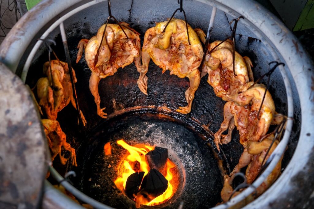 Delicious roasted chicken hanging over open flames, capturing the essence of traditional street food grilling.