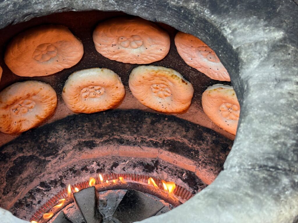 Close-up of bread baking on the walls of a traditional tandoor oven.